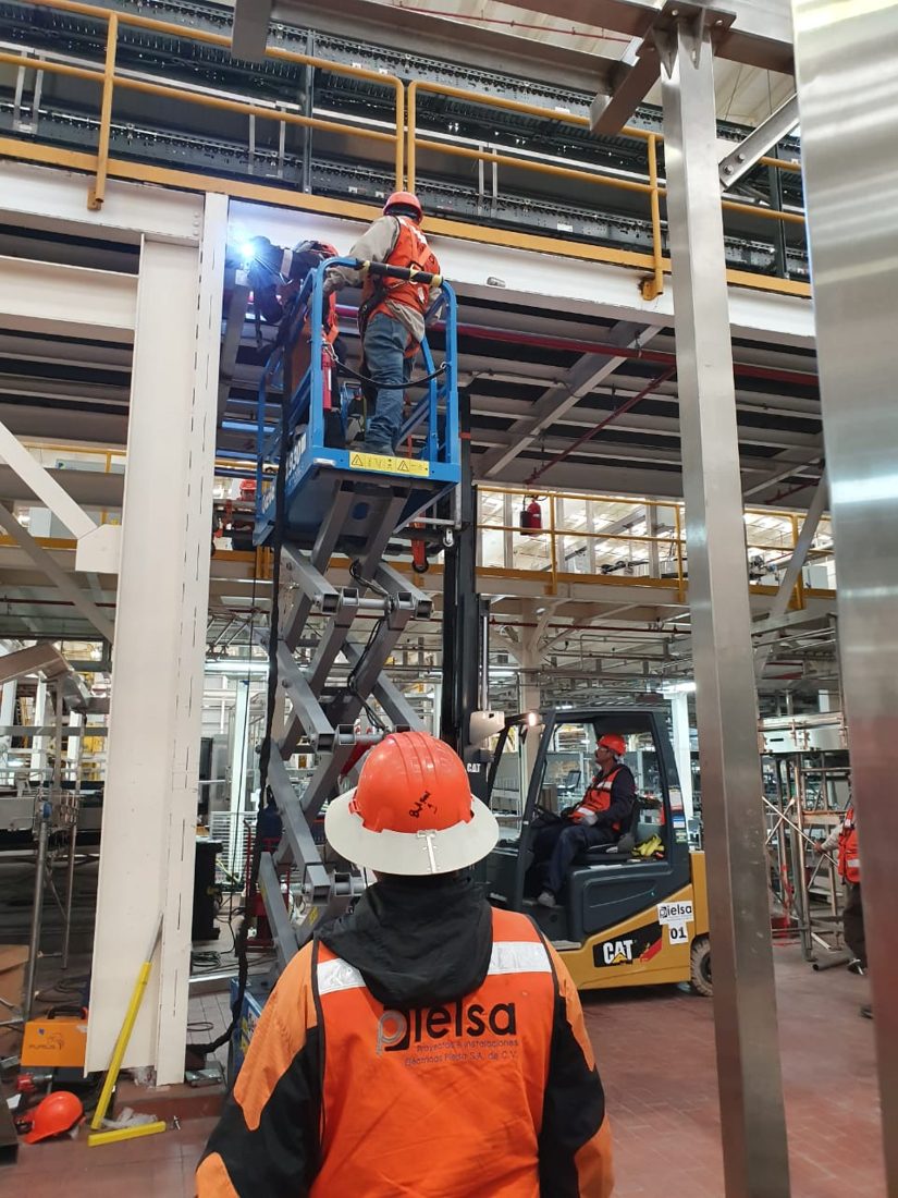 Plataforma de tijera el&eacute;ctrica junto a montacargas en planta